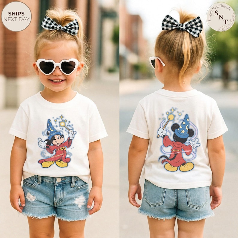 Op de afbeelding: Een kind draagt een wit t-shirt met een cartoonafbeelding van Mickey Mouse als tovenaar. Mickey, met een tovenaarsmuts, houdt een toverstaf vast. Het kind draagt ook een spijkerbroekshort en hartvormige zonnebrillen.