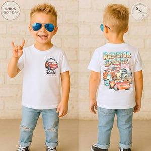 May include: White t-shirt featuring a cartoon car design with the name "David" printed below. The back of the shirt displays "Radiator Springs" with various car characters. The child is wearing blue sunglasses and ripped jeans.
