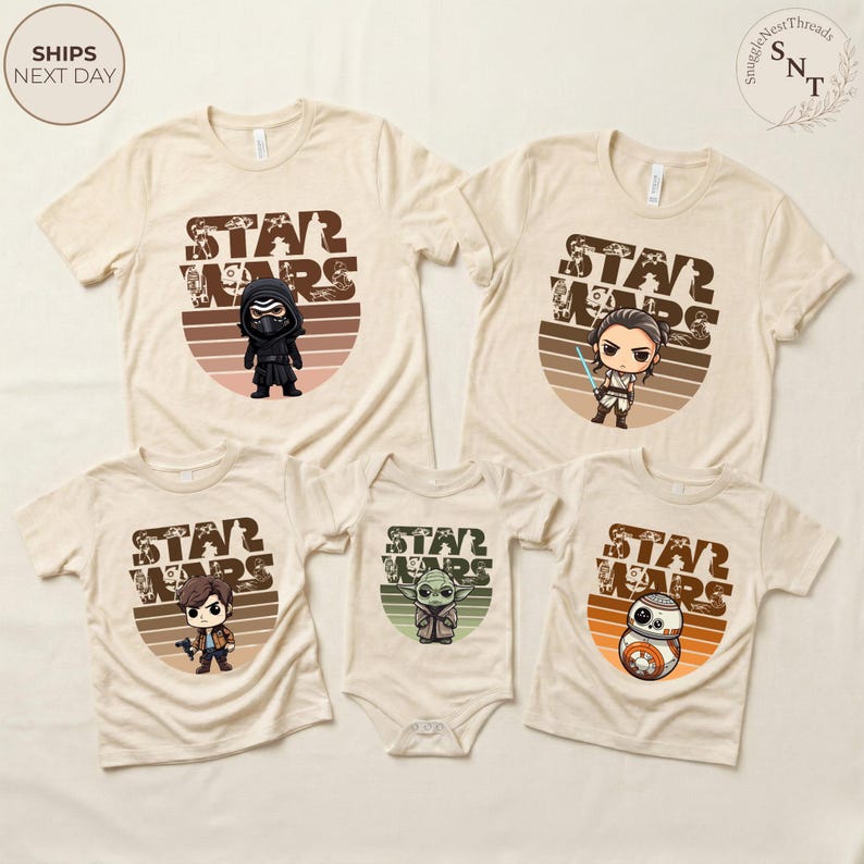 May include: Beige Star Wars themed t-shirts and a onesie. Each shirt features a different character graphic with the words "STAR WARS" in a brown, retro-style font. The shirts have short sleeves and a crew neck.