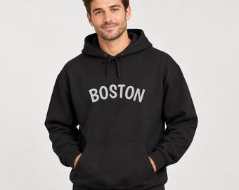 May include: A black hooded sweatshirt featuring the word BOSTON in large, light gray, arched block letters across the chest. The garment includes a front kangaroo pocket, long sleeves with ribbed cuffs, and a matching black drawstring at the neck.