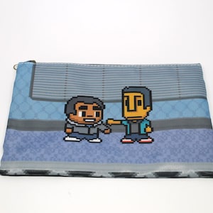 May include: A blue and gray zippered pouch with a pixelated image of two cartoon characters. The characters are wearing blue and gray jackets and are standing on a blue and gray tiled floor.