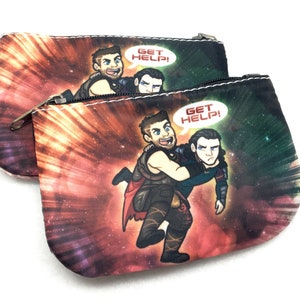 Puede incluir: Dos estuches con cremallera con estampado de galaxia y una imagen de dibujos animados de dos hombres. Los hombres llevan trajes de superhéroes y uno está sujetando al otro. El texto "Get Help!" está en un bocadillo de diálogo sobre los hombres.