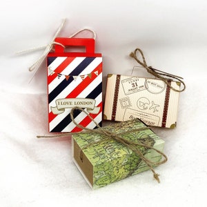 May include: Three small gift boxes decorated with travel themes. One box is red and white striped with the text "I Love London". Another box is brown with a vintage suitcase design and the text "Bon Voyage". The third box is green and brown with a world map design.