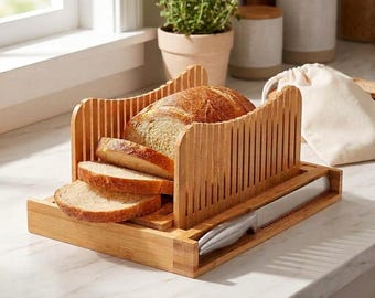 May include: A bamboo bread slicer guide with vertical slots for consistent cutting. The wooden unit holds a loaf of bread with three pre-cut slices resting in front. A serrated stainless steel bread knife is stored in a side compartment.