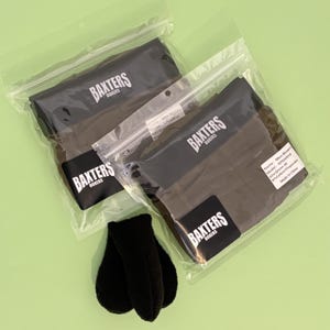 以下が含まれることがあります： 白い文字でBAXTERS BOXERSと書かれた黒いウエストバンド付きのオリーブグリーンのボクサーパンツが入った透明なプラスチック袋2つ。各袋には製品詳細が記載された白いラベルが付いています。袋の前には黒い布製のポーチが2つあります。