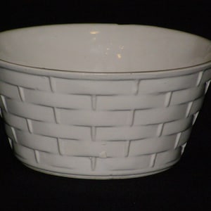 May include: White ceramic bowl with a woven basket pattern. The bowl is round and has a wide rim.