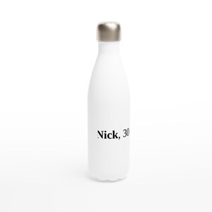 May include: White insulated water bottle with a silver cap. The text "Nick, 30" is printed in black on the front of the bottle. The bottle is designed to keep beverages cold for hours.
