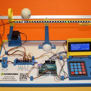 May include: A yellow, blue, and white electronic control system with a ball on a beam. The system includes a display screen, keypad, and circuit board. The text "ESTUDIO ROBLE Control PID de Barra y Bola con Arduino [v2].kit" is visible.