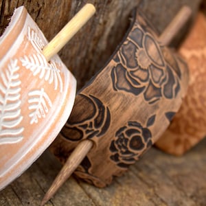 Puede incluir: Tres palos de pelo de madera con dise&ntilde;os decorativos. Los palos son marrones y tienen un acabado natural. Los dise&ntilde;os est&aacute;n tallados en la madera e incluyen helechos, rosas y un patr&oacute;n floral. Los palos miden aproximadamente 25 cm de largo.