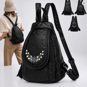 May include: A black backpack with a textured finish, featuring a front flap adorned with a braided border and a floral embroidery pattern. The bag includes adjustable shoulder straps, side zippers, and a top handle, showcasing a versatile design.