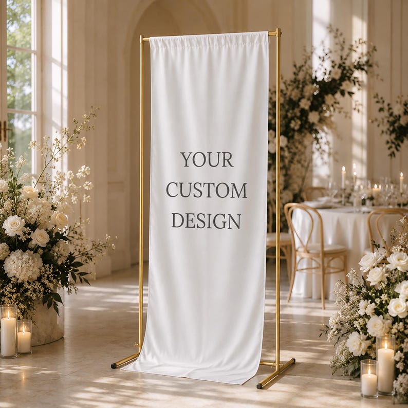 May include: A white banner with the text "YOUR CUSTOM DESIGN" displayed on a gold metal stand. The banner is in a room with floral arrangements and candles, suggesting a wedding or event setting.