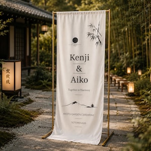 May include: A white banner with black text and illustrations, displayed on a gold metal stand. The banner reads "Kenji & Aiko" with "Together in Harmony" below. Additional text includes "Kyoto Garden Ceremony" and "October 2026".