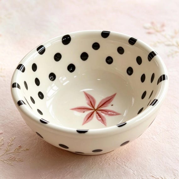 Hand-painted ceramic bowl dripping with pink florals and polka dots — whimsical studio pottery energy that makes dessert feel like an occasion.