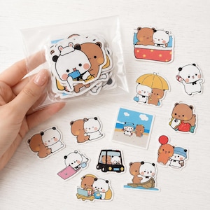 May include: A collection of die-cut stickers featuring cartoon bears in various activities, including a clear plastic bag filled with multiple stickers and several loose stickers depicting bears hugging, driving a car, and using a laptop.