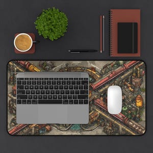 May include: A rectangular desk mat featuring an intricate, detailed illustration of a complex industrial railway system with red trains, pipes, and metallic structures. A silver laptop and a white computer mouse are placed on the mat.