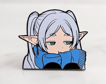 Könnte beinhalten: Metall-Anstecknadel mit einem Anime-Charakter mit silbernem Haar, grünen Augen und spitzen Ohren. Der Charakter trägt ein blaues Outfit und hat einen traurigen Gesichtsausdruck. Die Anstecknadel befindet sich auf weißem Grund.