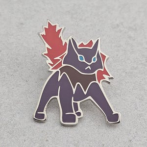 Puede incluir: Un pin de esmalte morado y rojo que representa una criatura estilizada con forma de gato, con ojos azules y una melena roja. El pin tiene un contorno plateado y está sobre un fondo gris claro. La criatura está en posición de caminar.