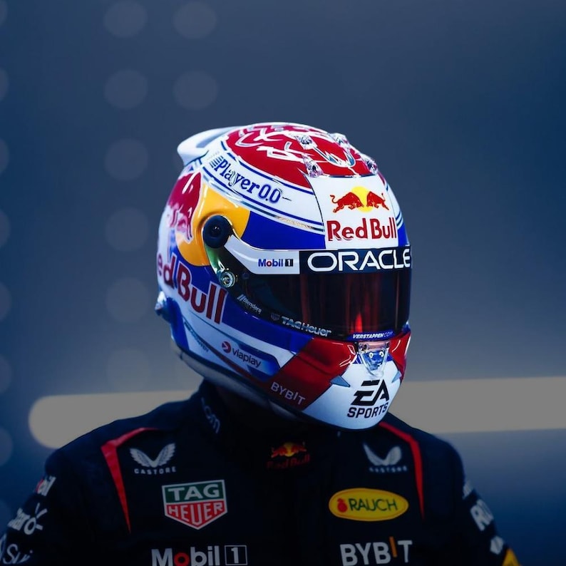 K&ouml;nnte beinhalten: Ein Rennhelm in den Farben Wei&szlig;, Rot und Blau mit auff&auml;lligem Red Bull, Oracle und EA Sports Branding. Der Helm verf&uuml;gt &uuml;ber ein dunkel get&ouml;ntes Visier und verschiedene Sponsorenlogos wie Player 0.0, Mobil 1 und Tag Heuer.