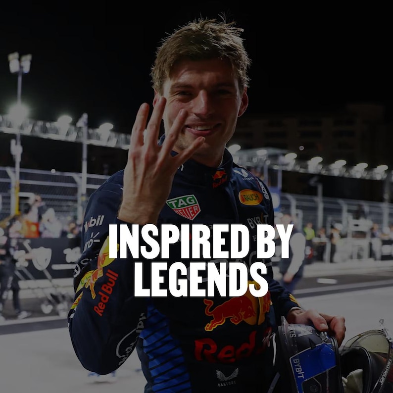 K&ouml;nnte beinhalten: Eine dunkelblaue Rennjacke mit roten und gelben Red Bull-Logos, einem TAG Heuer-Logo und dem Text INSPIRED BY LEGENDS. Die Jacke hat blaue Seiteneins&auml;tze, einen hohen Kragen und wei&szlig;e Sponsorenlogos auf den &Auml;rmeln und im Brustbereich.