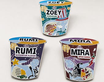 Könnte beinhalten: Drei Emaille-Anstecknadeln in Form von Instant-Nudelbechern. Jede Anstecknadel hat ein anderes Design mit den Namen "ZOEY", "RUMI" und "MIRA". Die "ZOEY"-Anstecknadel hat ein Hamburger-Thema, "RUMI" hat einen Stern und "MIRA" hat eine Chilischote.
