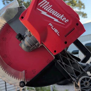 Puede incluir: Una sierra ingletadora roja Milwaukee Fuel con una hoja circular y un protector de plástico transparente. La herramienta tiene una carcasa de motor roja con la marca blanca Milwaukee y Fuel, un mango negro y un marco de soporte gris.