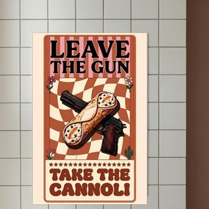 May include: Poster with a retro design featuring a gun and a cannoli. The text reads "LEAVE THE GUN TAKE THE CANNOLI" in a vintage font. The background has a checkered pattern in shades of brown and cream.