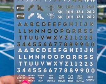 May include: A clear sticker sheet featuring gold and white adhesive decals including stars, lightning bolts, flames, running shoes, race distances like 5K and 26.2, the full alphabet, numbers 0-9, and motivational phrases like MIND OVER MILES.