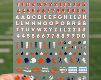 May include: A clear sheet of adhesive decals featuring orange and white letters, numbers, and sports-themed icons including footballs, helmets, stars, bear paws, jerseys, and the text CHI TOWN, BEAR DOWN, GOOD BETTER BEST, and Chicago flag designs.