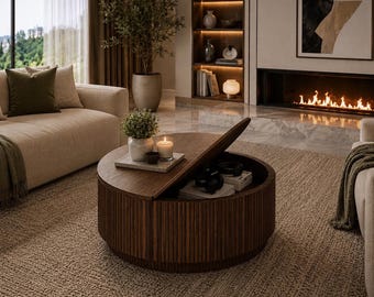 Puede incluir: Una mesa de centro redonda de madera oscura con listones verticales en el exterior. La mesa cuenta con una tapa abatible parcialmente abierta que revela un compartimento de almacenamiento interior con auriculares y libros, y una vela encima.