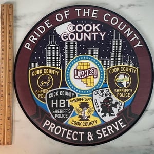 May include: A round patch with the text "PRIDE OF THE COUNTY" and "PROTECT & SERVE". The patch features a skyline, multiple badges, and the words "COOK COUNTY" in various places. The patch is approximately 10 inches in diameter.