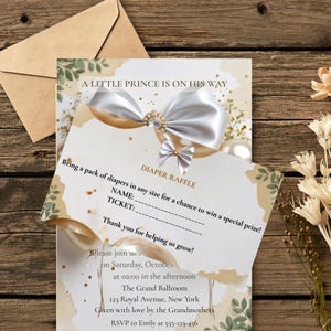 Pode incluir: Um conjunto de convite para chá de bebê e cartão de rifa de fraldas com paleta de cores branco e dourado, um gráfico de laço de cetim grande com centro de joia e texto lendo A LITTLE PRINCE IS ON HIS WAY e DIAPER RAFFLE com linhas.