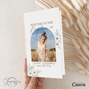 May include: A white card with a blue archway and a photo of a young girl in a white dress. The text "Welcome to the Baptism of Emma Williams June 14th, 2025" is printed on the card.