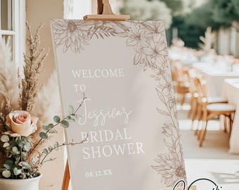 May include: A welcome sign for a bridal shower with a floral design. The sign is beige with white text that reads "Welcome to Jessica's Bridal Shower 08.12.XX".