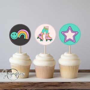 Könnte beinhalten: Drei Cupcake-Topper mit einem Regenbogen-Smiley, einem Paar Rollschuhen und einem Stern. Die Topper befinden sich auf Cupcakes mit weißem Frosting.