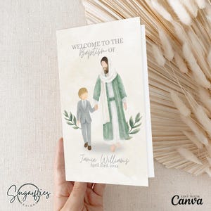 Puede incluir: Una tarjeta de invitación de bautizo con una ilustración en acuarela de una figura con una túnica blanca y un niño con un traje gris. El texto "WELCOME TO THE BAPTISM OF" está en la parte superior, con el nombre "Jamie Williams" y la fecha debajo. La tarjeta es sostenida por una mano.