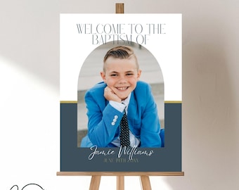 Puede incluir: Un cartel de bienvenida para un bautizo con una foto de un niño pequeño con un traje azul y una camisa blanca con corbata. El cartel tiene un arco dorado y azul con el texto "Bienvenido al Bautizo de Jamie Williams 18 de junio de 20XX".