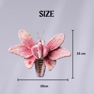 May include: A pink butterfly hair claw clip with soft velvet-like texture, gold thread embroidery on the wings, and two thin antennae. The clip measures 15 cm by 15 cm as indicated by the text and measurement lines labeled SIZE in the image.