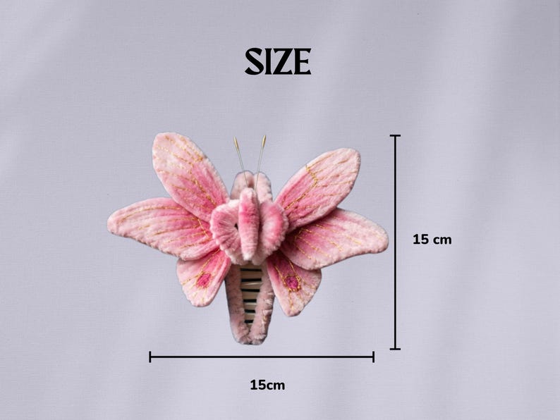 May include: A pink butterfly hair claw clip with soft velvet-like texture, gold thread embroidery on the wings, and two thin antennae. The clip measures 15 cm by 15 cm as indicated by the text and measurement lines labeled SIZE in the image.