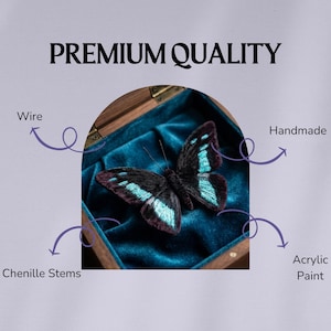 May include: A handmade butterfly made with chenille stems, wire, and acrylic paint, displayed in a wooden box with a teal velvet lining. The butterfly has black and teal wings. The text "PREMIUM QUALITY" is at the top.