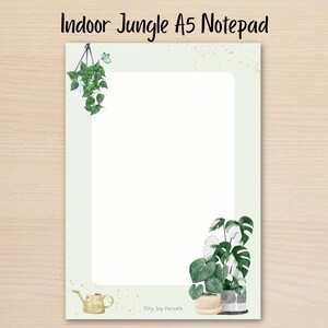 May include: An A5 notepad with a light green border and a white centre. The design features a hanging plant in the top left, a potted monstera plant in the bottom right, and a small watering can in the bottom left. The text reads Indoor Jungle A5 Notepad.