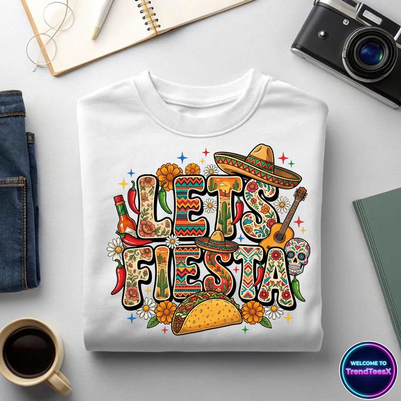May include: White crewneck sweatshirt with a colorful "Let's Fiesta" graphic. The design includes sombreros, a guitar, a taco, chili peppers, and floral elements. A festive and fun design for a celebration.