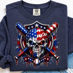 May include: A navy blue crewneck sweatshirt featuring a graphic of a skull with a melting American flag pattern, positioned in front of two crossed baseball bats. A baseball sits below the skull, all set against a shield and star background.