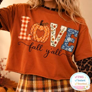 May include: A burnt orange sweatshirt featuring the word LOVE in large, patterned letters. The L is red and white gingham, the O is an orange pumpkin with a heart cutout, the V is floral, and the E is blue floral. Below, the text fall y'all is printed.