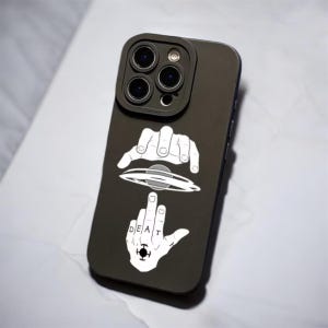 Könnte beinhalten: Dunkel olivgrüne Handyhülle mit einem grafischen Design mit weißen Händen, einem UFO und dem Wort "DEAT" mit einem Symbol. Die Hülle hat einen Kameraschutz.