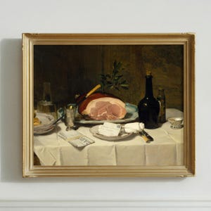 May include: A framed oil painting depicting a still life scene on a white tablecloth. A large sliced ham sits on a platter with a knife and green sprig. Nearby are a dark glass bottle, a silver goblet, a small plate with a note, and a folded newspaper.