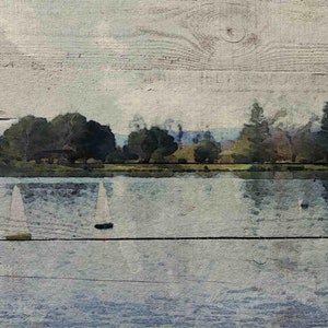 May include: A watercolor painting of a lake with sailboats in the distance. The lake is surrounded by trees and the sky is a light blue. The painting is on a wooden background.