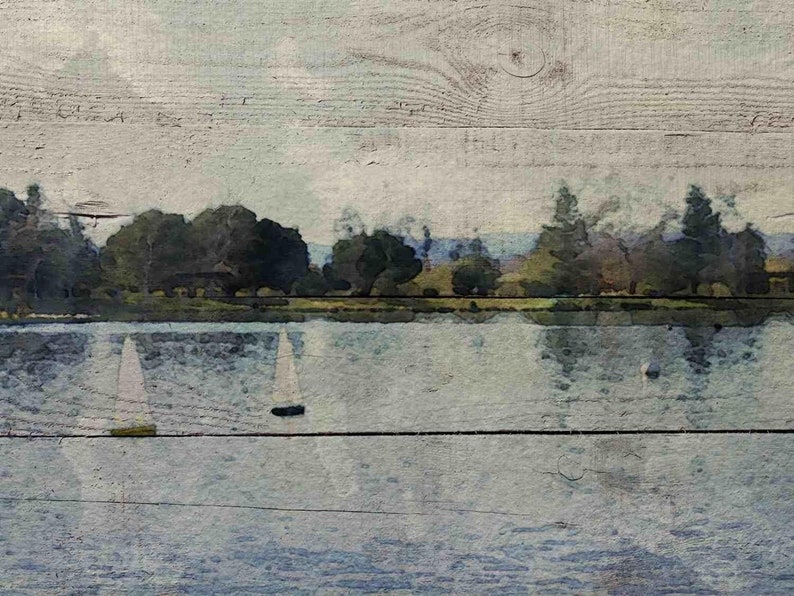 May include: A watercolor painting of a lake with sailboats in the distance. The lake is surrounded by trees and the sky is a light blue. The painting is on a wooden background.