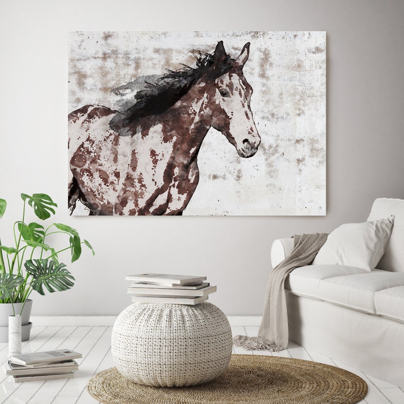 May include: A large canvas print featuring a watercolor-style painting of a horse. The horse is depicted in shades of brown and white against a textured, off-white background. The artwork captures the horse in motion, with its mane flowing.