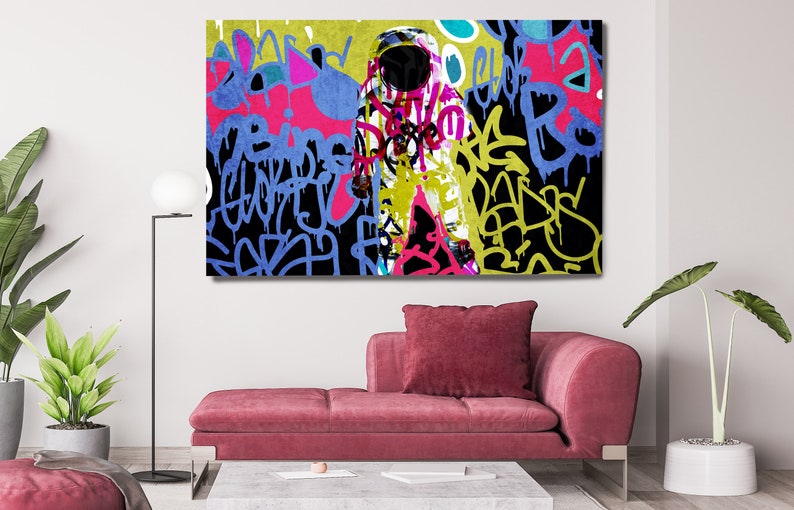 May include: Abstract art print featuring a colourful astronaut figure with graffiti-style lettering in shades of blue, yellow, pink, and black.