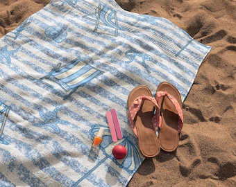 Toalla de playa a rayas azules con diseño náutico de conchas marinas y estrellas de mar. Vacaciones de verano.